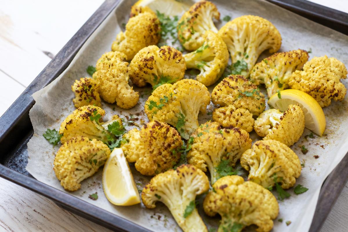 Bouquets de chou-fleur rôtis aux épices dorés sur une plaque, citron et persil