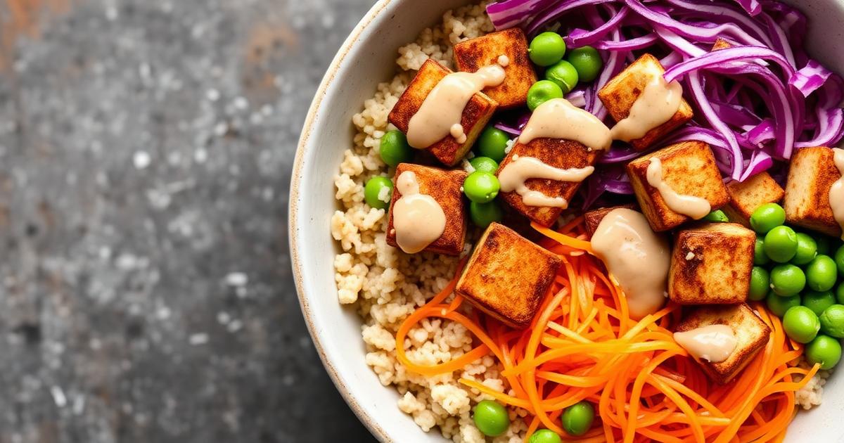 Buddha bowl vegan avec tofu croustillant, quinoa, carotte râpée, chou rouge, edamame et sauce tahini