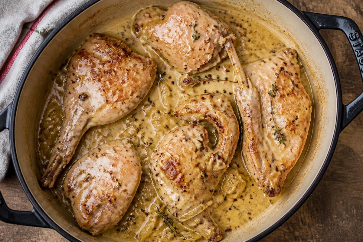 Morceaux de lapin dorés mijotés en cocotte dans une sauce moutarde onctueuse au thym